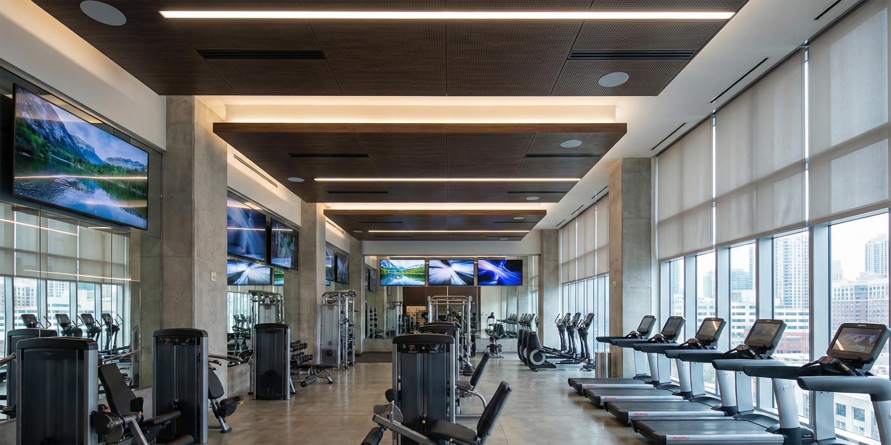 Modern fitness center with treadmills, strength machines, and wall mounted screens
