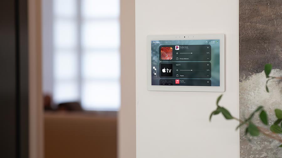 Wall mounted smart home touchscreen controlling music and TV in a modern interior