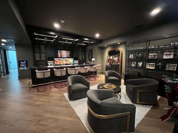 Basement sitting lounge facing custom black bar under dark ceiling with geometric light lines