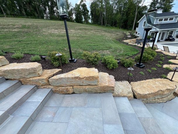Stone patio steps looking up at a sloped lawn with outdoor path lights and post fixtures