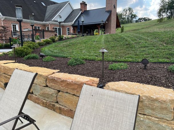 Backyard patio with stone retaining wall highlighting path lighting and landscape audio