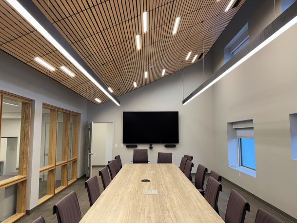 Sleek corporate conference room focusing on a long table and large wall display monitor