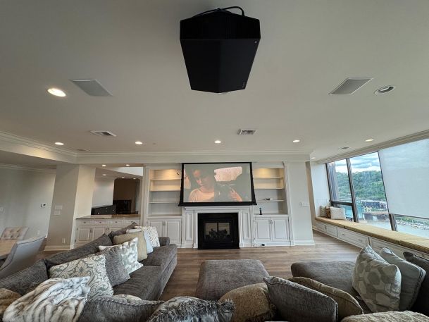Large open living space showcasing a ceiling mounted projector aligned with a drop screen