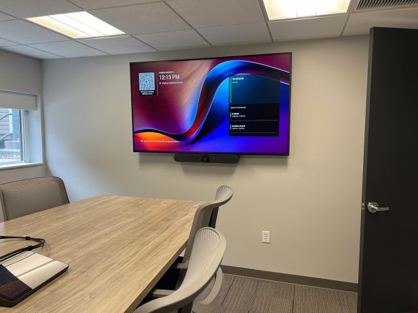 Modern conference room featuring wall television screen presenting schedule interface