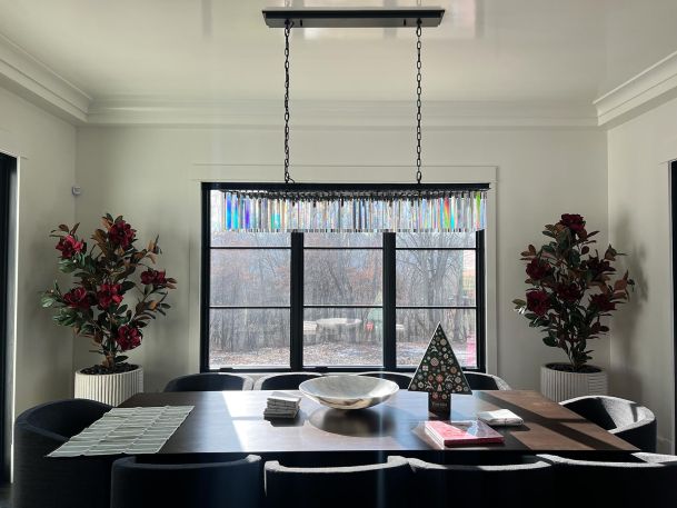 Formal dining table underneath a long modern rectangular colorful glass pendant chandelier