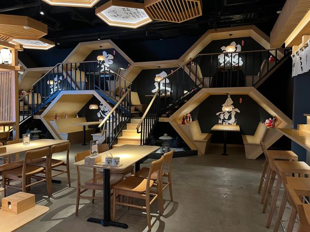 Hexagonal multi level dining booths inside a modern restaurant with black background walls