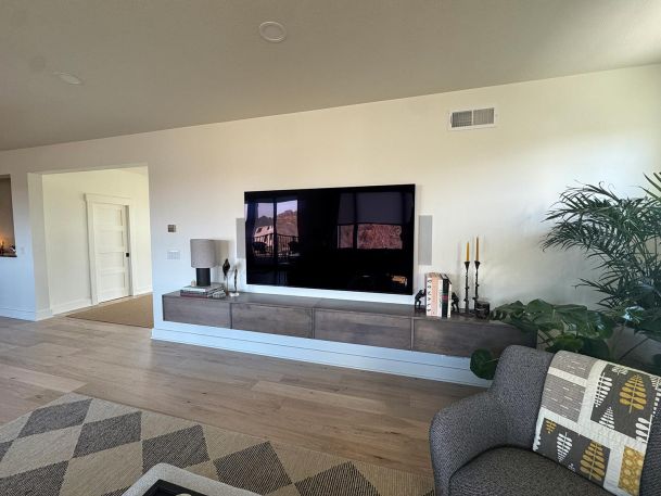 Large thin bezel media display screen mounted over custom floating wood entertainment console