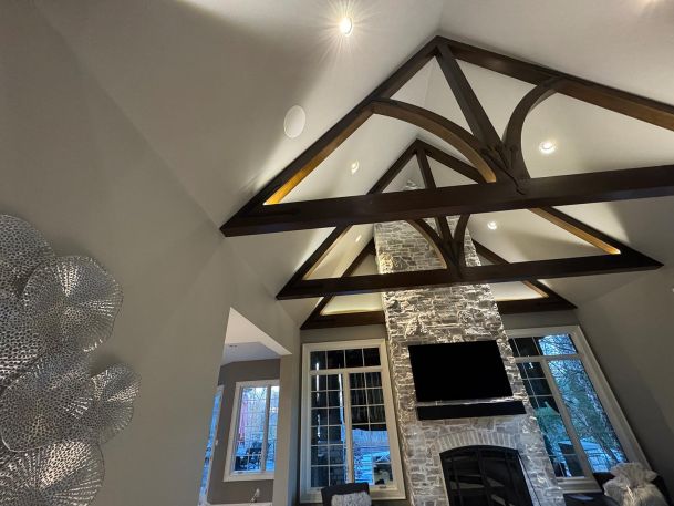 Angled view of a rustic living room ceiling showing wood beams and inset white speakers