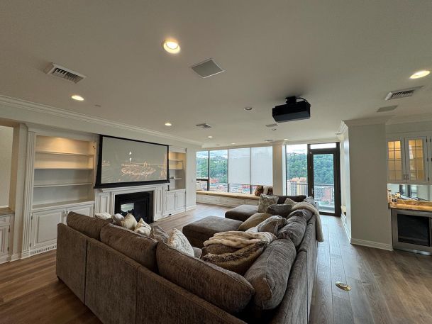 Living room with sectional sofa looking toward a black home theater video projector hanging