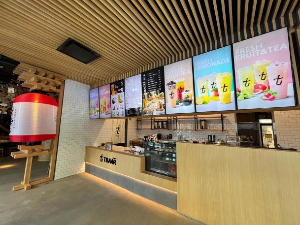 Restaurant ordering counter with digital menu boards suspended from wood slat ceiling