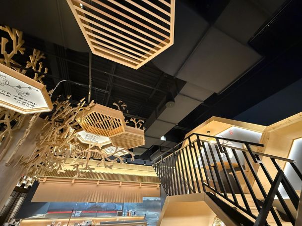 Modern commercial interior highlighting geometric wooden ceiling hangings and staircase