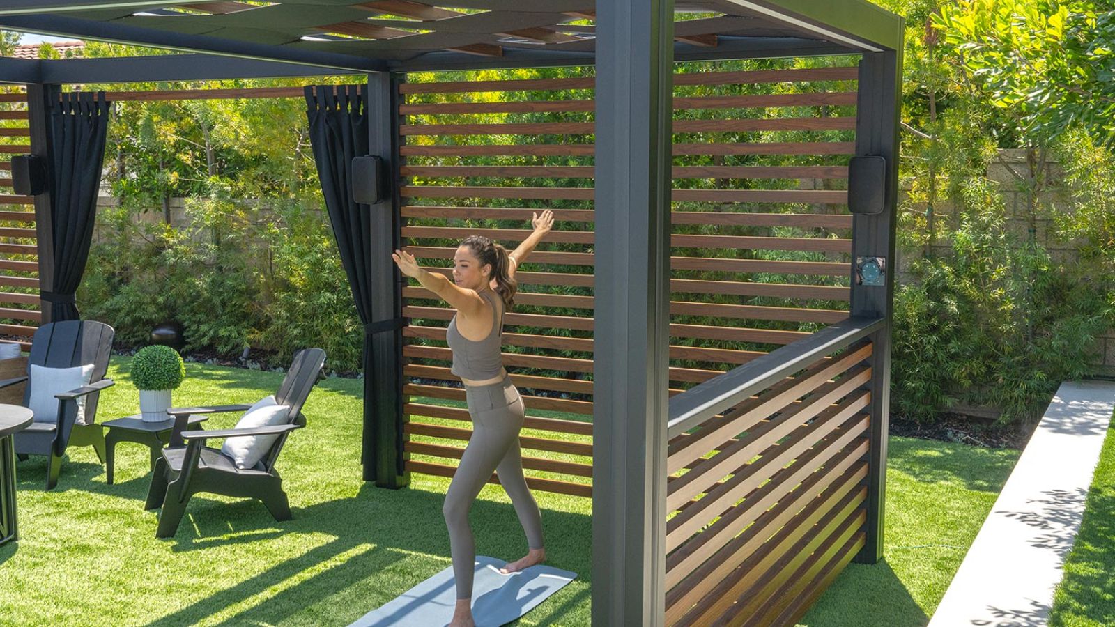 A  woman practicing yoga outdoors on a patio, surrounded by greenery.