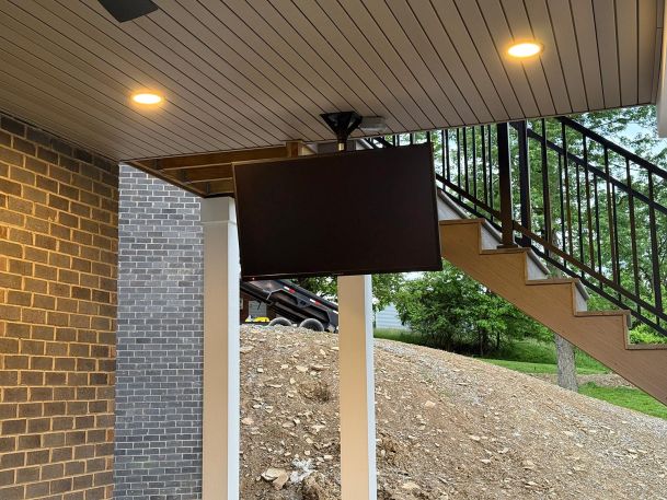 Close up of an outdoor television screen securely mounted to the ceiling of a covered deck