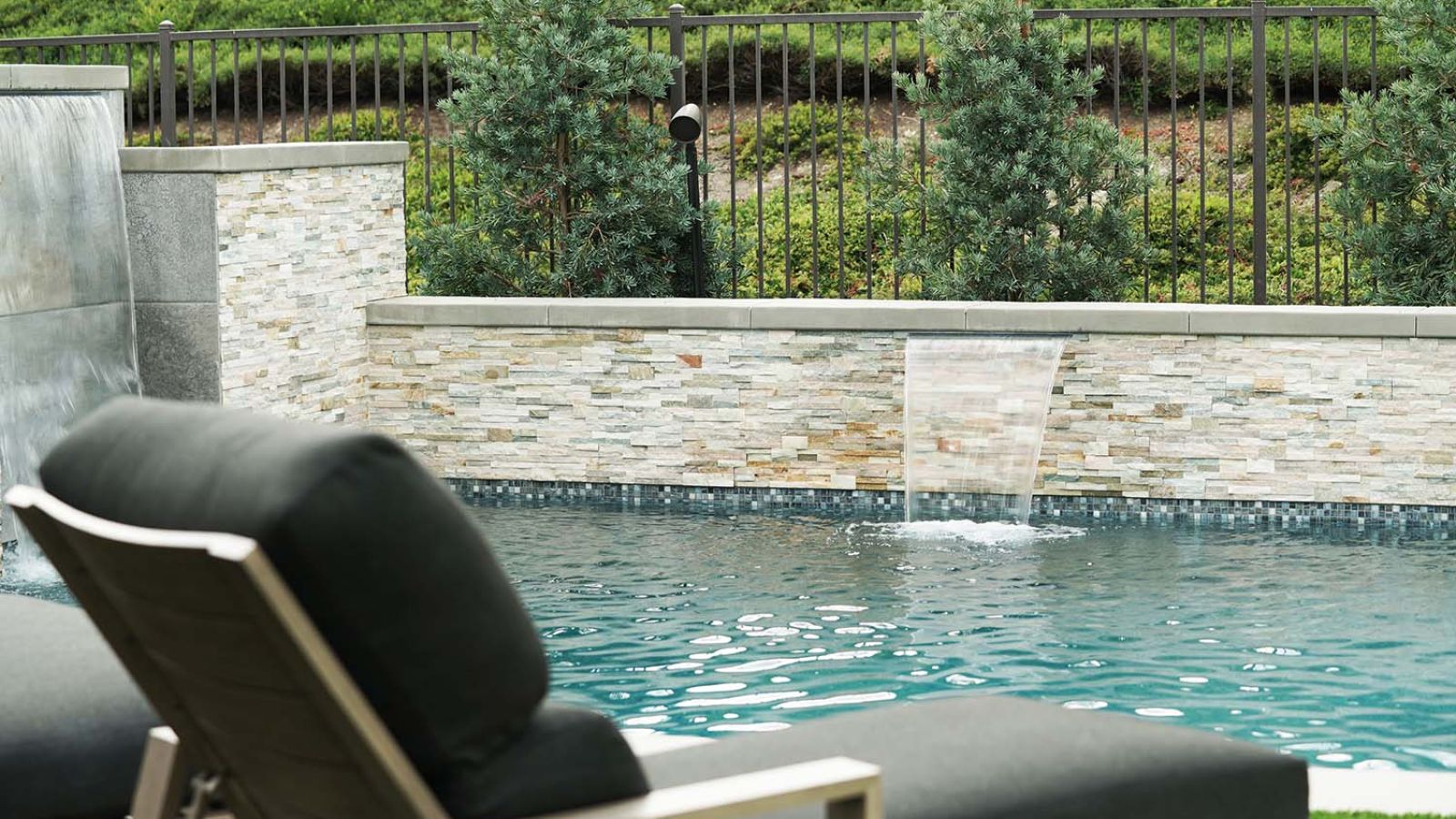 A stylish outdoor pool with a Sonance speaker