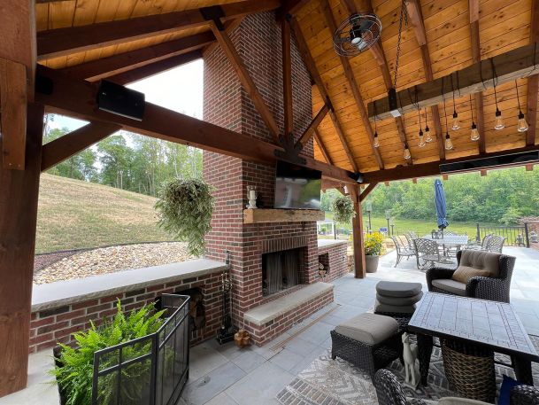 Covered outdoor brick pavilion patio featuring a fireplace and wall mounted television