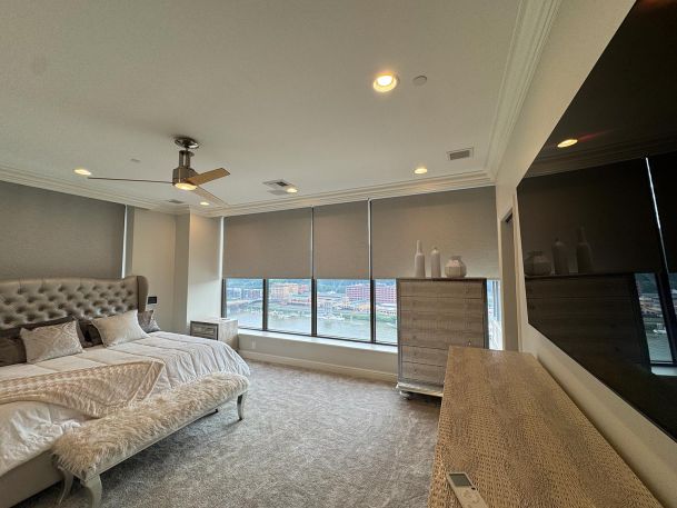 Master bedroom interior capturing wide windows with automated roller shade fabrics
