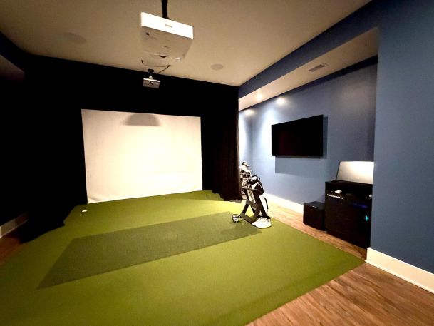 Private indoor golf simulator facility equipped with ceiling projector and hitting screen