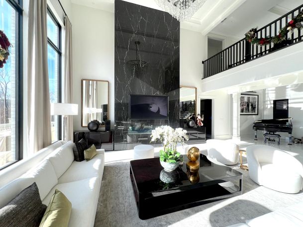 Bright luxury living room featuring tall windows and central black fireplace accent column