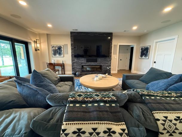 Cozy family room centered on a stone fireplace containing inset television and black speakers