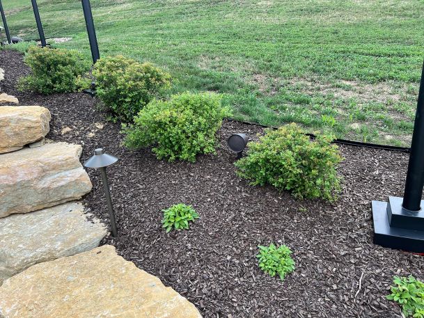 Outdoor garden bed with metal path light and small directional spotlight fixture near stones