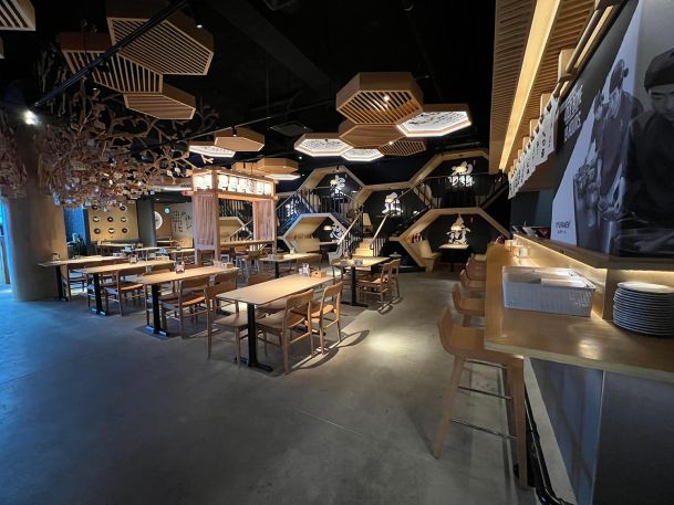 Wide angle view of an upscale restaurant dining room with hanging wooden lantern structures