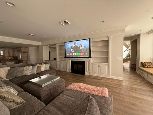 Large basement living room featuring a motorized projection screen lowered over fireplace