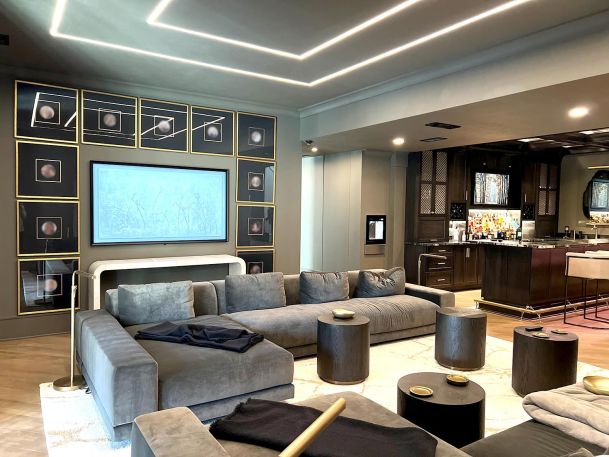 Modern basement room showing digital media frame over white console table near black wet bar