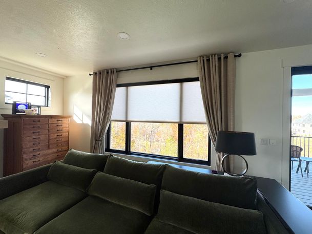 Bedroom window overlooking trees featuring fully raised light filtering roller shades