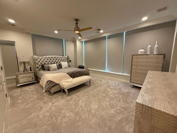 Spacious master bedroom with fully lowered gray motorized roller window treatments