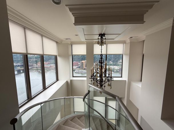 Spiral staircase overview showing windows with matching roller shades and crystal chandelier