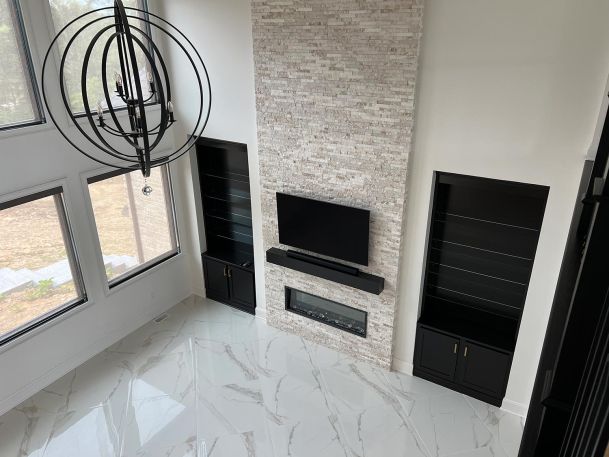 High angle view of a white living room with marble floors and television over fireplace