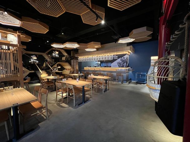 Full view of a modern restaurant interior with decorative ceiling panels and booth seating
